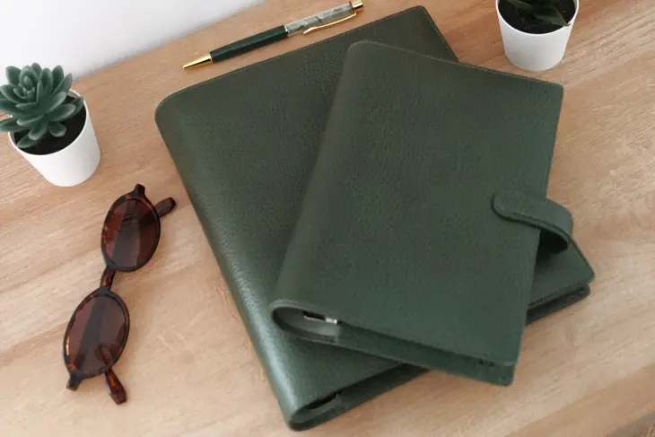 Auf einem Tisch liegen zwei grüne Organizer von Filofax