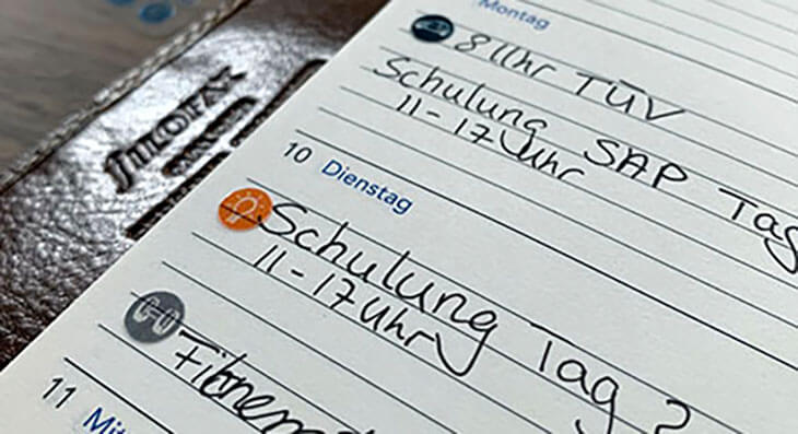 Detailaufnahme einer Seite aus einem Kalender von Filofax. Kleine Sticker kennzeichnen mit der Colour-Coding-Methode unterschiedliche Themenfelder. 