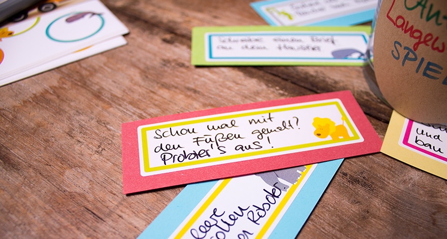 Nahaufnahme von 2 Aufgaben-Kärtchen, welche mit den Aufklebern zur Kennzeichnung von Spielzeug beklebt sind. Auf einem Sticker ist ein Löwe zu sehen, auf dem anderen ein Elefant.