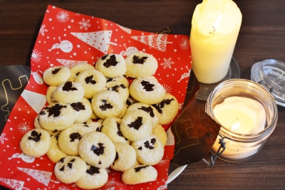 Auf einem Tisch steht ein Teller mit selbstgebackenen Luciaplätzchen. Daneben stehen zwei Kerzen als Deko.