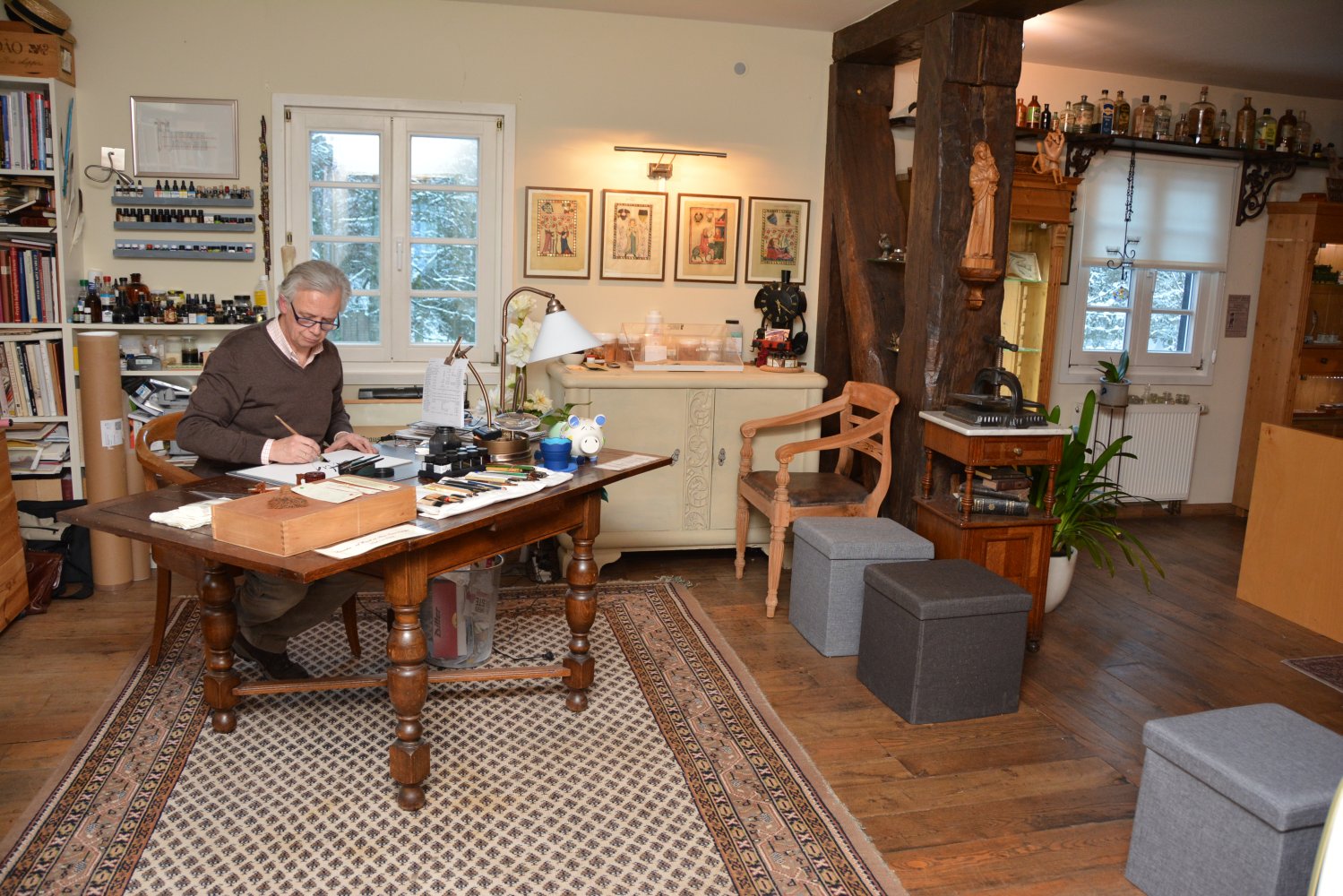 Martin Heickmann sitzt in seinem Museum am Schreibtisch und kalligrafiert etwas auf einem Blatt Papier.