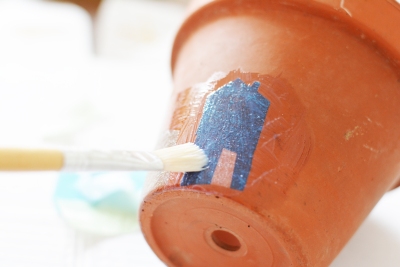 Motiv wird mit Transferlack auf eine Tontopf übertragen.