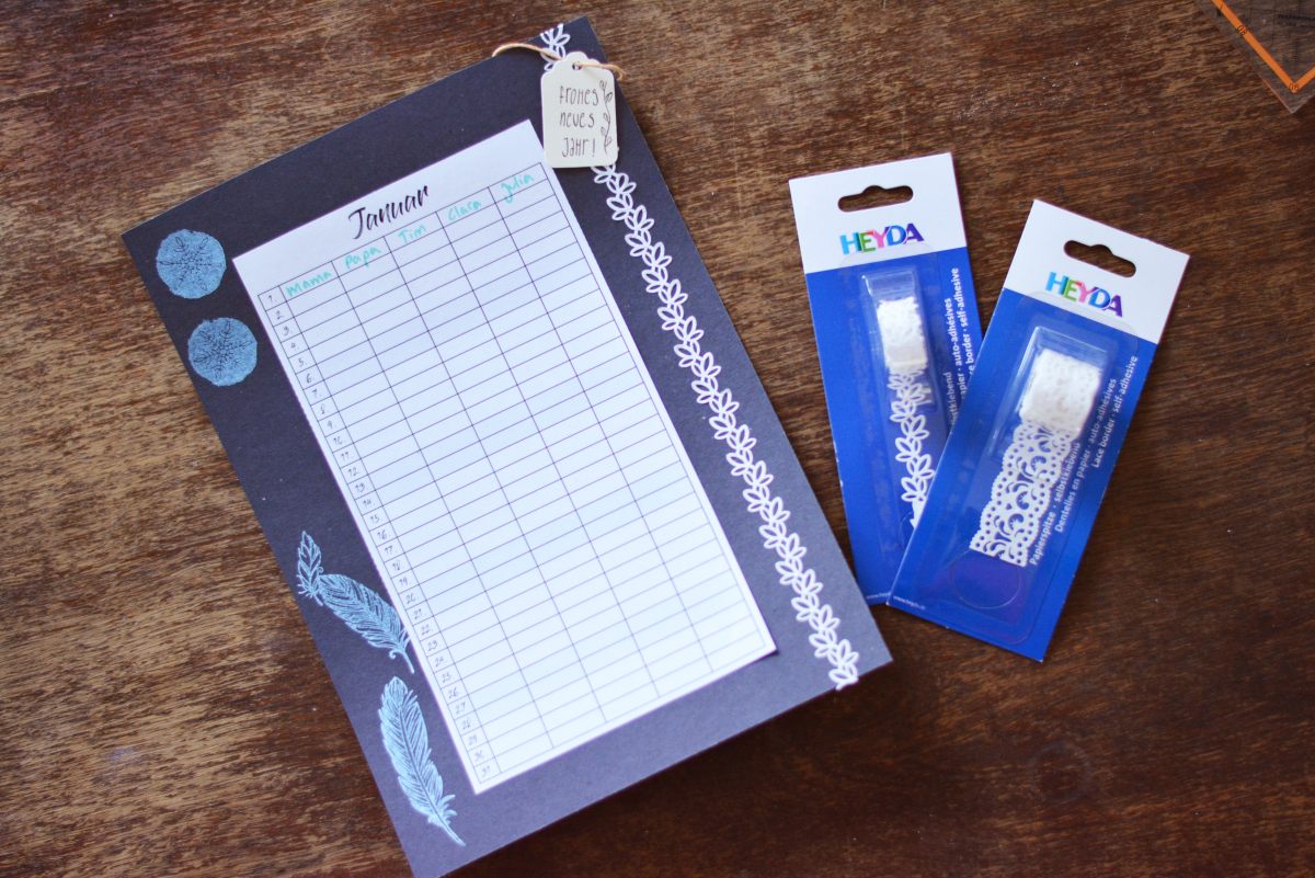 Januar-Planer auf schwarzem Karton mit Spitzenband und Geschenkanhängern von Heyda