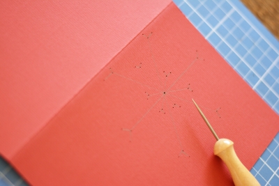 Löcher mit Prickelnadel in roter Karte für Schneeflocke