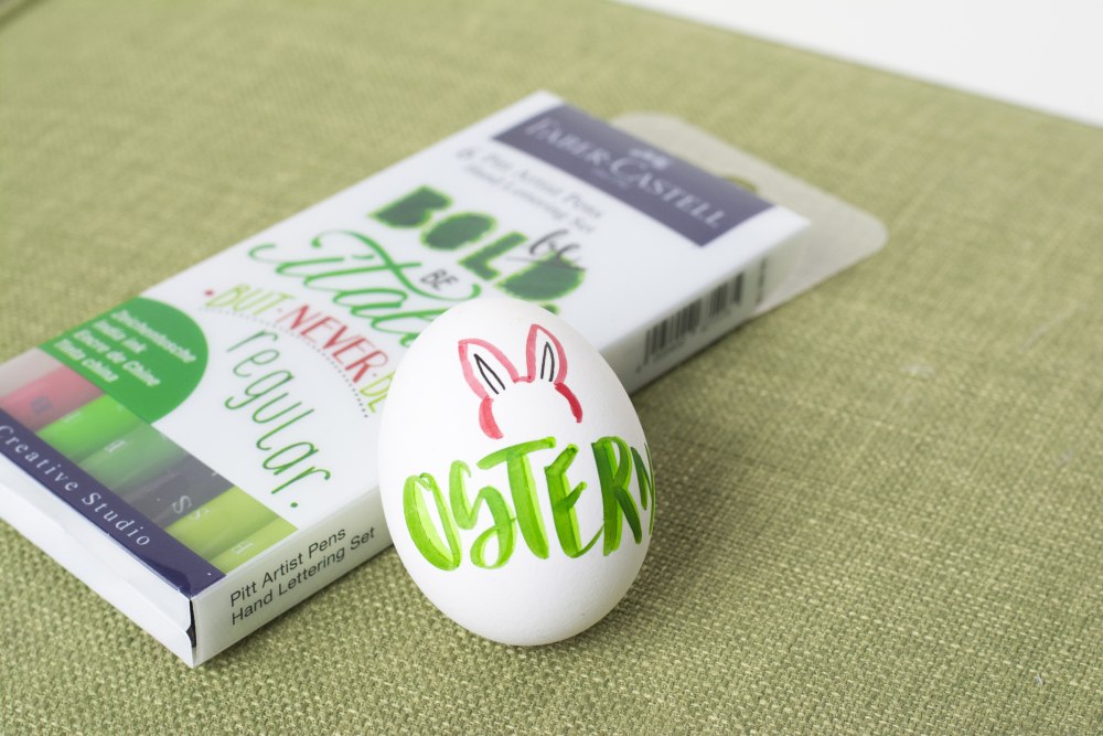 Ei mit Oster-Schriftzug neben Faber-Castell-Stifte-Set
