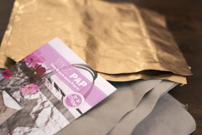 Metallicgolg- und graues SnapPap-Papier liegt mit Verpackung auf Tisch