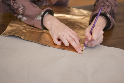 Hände zeichnen Umrisse auf SnapPap-Vorlage mit goldenem Glanz