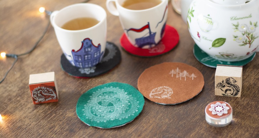 Filzuntersetzer mit Stempeln und Teetassen auf einem Holztisch