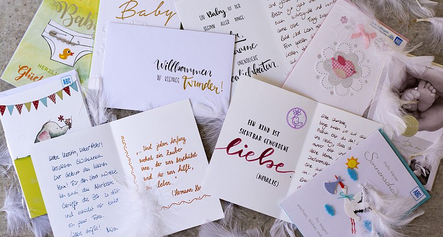 Viele unterschiedlich gestaltete Karten zur Geburt der Marke ABC liegen auf einem Tisch verteilt.