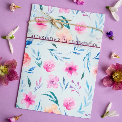 Geburtstagskarte mit Blumenmotiv, Schleife und Blüten auf lila Untergrund