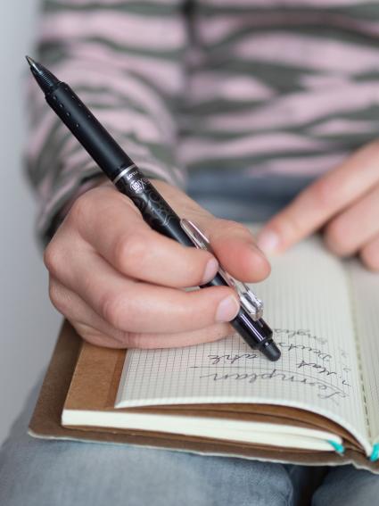 Mit Hilfe eines Frixion Pens von Pilot wird ein Eintrag in einem Notizheft korrigiert.