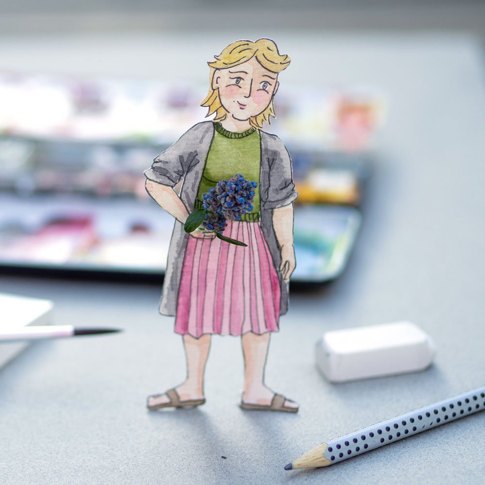 Bunte illustrierte Figur einer Frau, aus Papier ausgeschnitten, aufgestellt auf einem Tisch