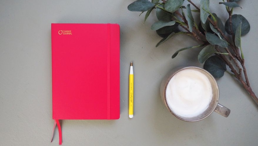 Flatlay eines pinken Change Journals von Leuchtturm1917, daneben liegt ein Drehgriffel der Marke Leuchtturm1917. Daneben steht eine Tasse Cappuchion und es liegen Eukalyptuszweige auf dem Tisch.