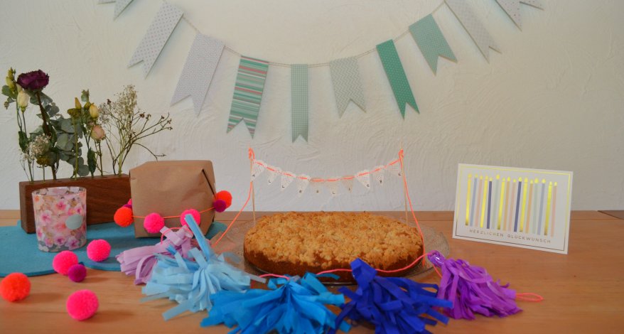 Geburtstagskuchen mit DIY-Girlande und farbenfroher Dekoration.