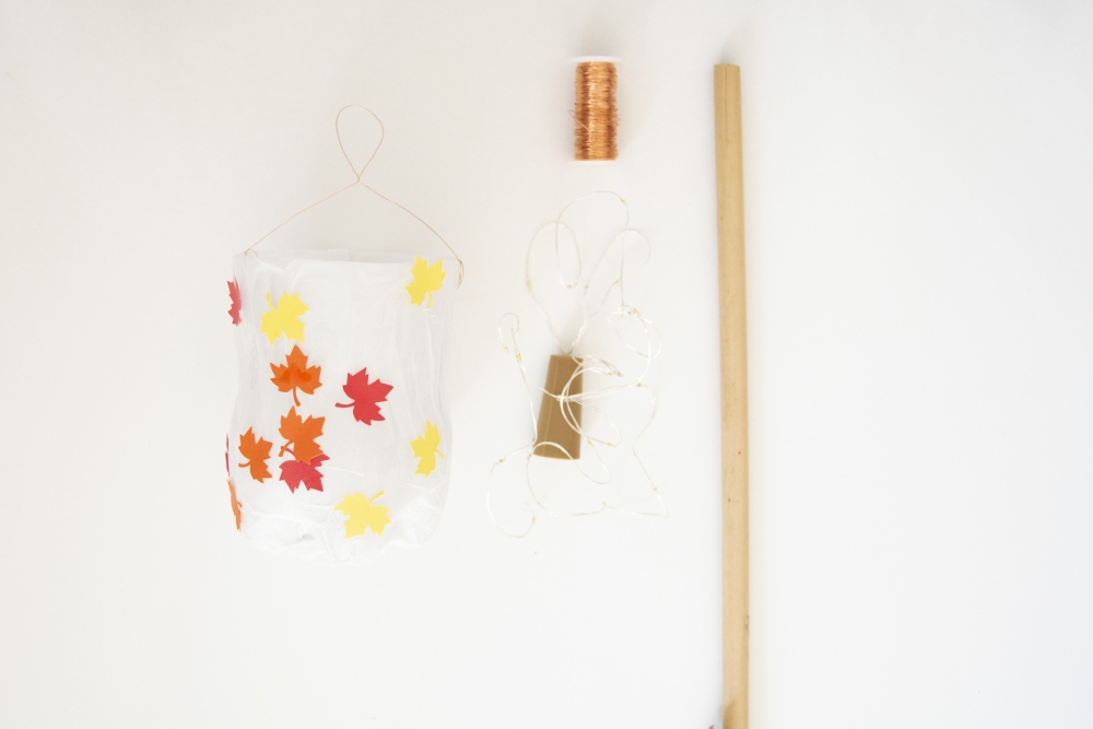 Selbstgebastelte Laterne aus PET-Flasche mit bunten Blättern, Draht, Lichterkette und Stab.