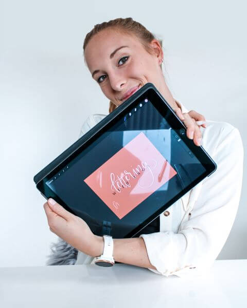 Portrait von Inga von ingasblog.com, die ein Tablet mit ihrem Lettering-Kurs in die Kamera hält.