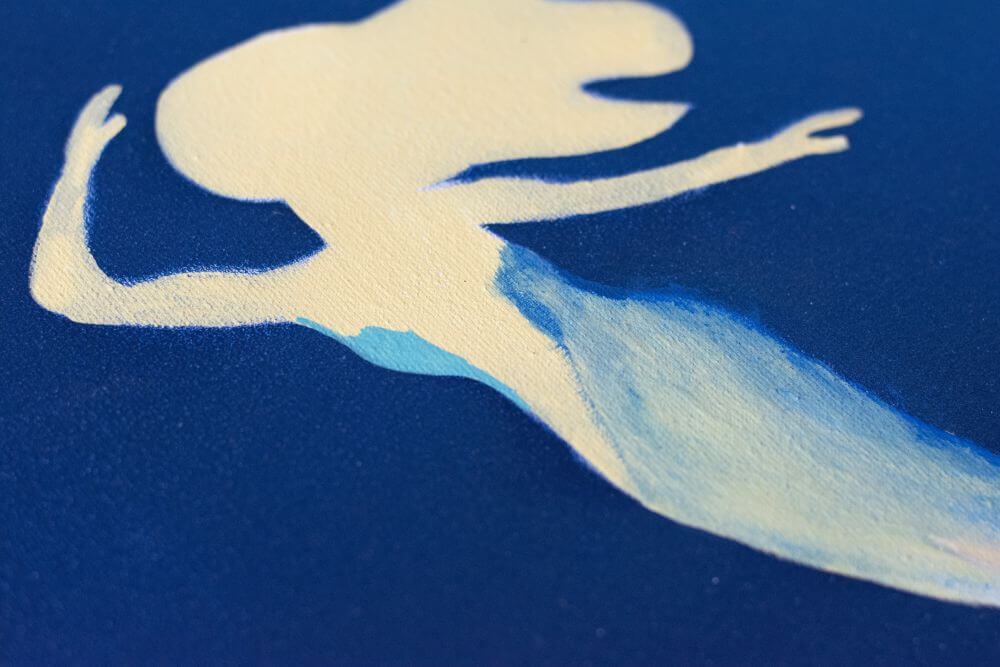 Nahafufnahme einer gemalten Meerjungfrau aus Acryl. Hellblaue Farbe ist an der Körperkontur aufgebracht, um sie zu verblenden.