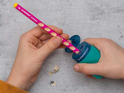 Ein Kind spitzt mit einem speziellen Linkshänder-Spitzer einen pinken Linkshänder-Bleistift von Stabilo. Foto: Johanna Rundel