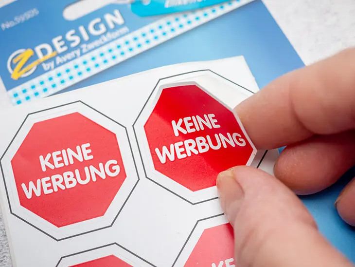 Jemand zieht einen „Keine Werbung“-Aufkleber von Avery Zweckform von einem Aufkleberbogen ab. Foto: Johanna Rundel