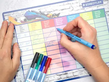 Jemand schreibt mit einem Stift von STAEDTLER auf einen abwischbaren Stundenplan einen Lernplan zur Vorbereitung auf Klassenarbeiten. Foto: Johanna Rundel