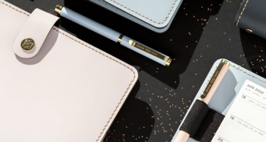 Nahaufnahme von Ecken mehrerer Filofax-Planer inkl. Stift. 