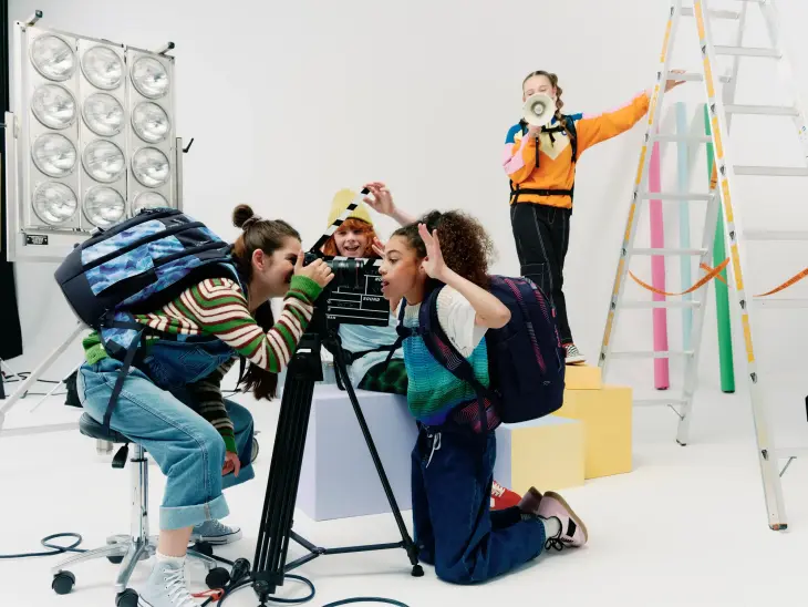 Kinder mit satch-Schulranzen auf den Rücken stehen in einem Film-Set.