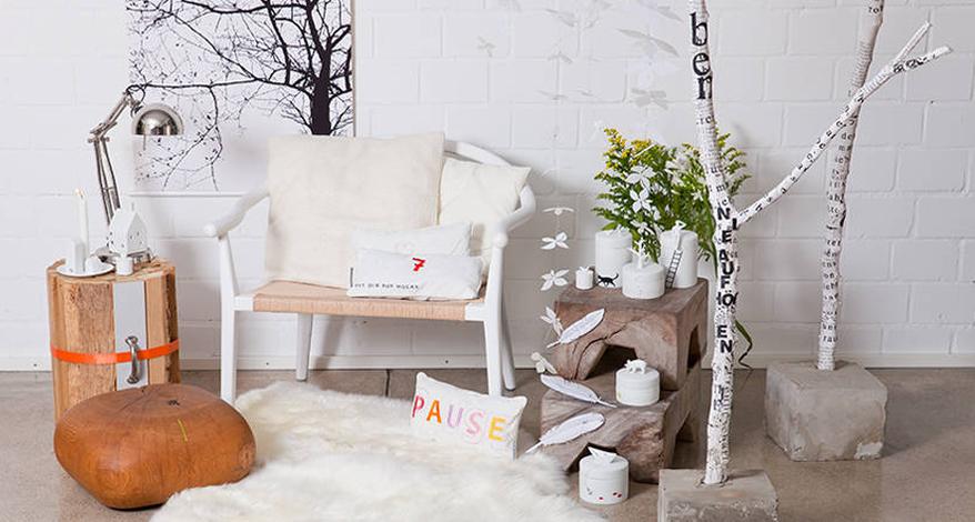 Helles Wohnzimmer mit Deko-Ästen, Dekomaterialien von räder sowie eine Bank, Kissen und Naturmaterialien.