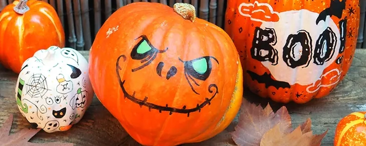 Drei unterschiedlich bemalte Halloween-Kürbisse.