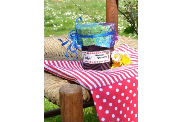 Auf einem Stuhl im Garten steht ein Marmeladenglas, welches mit einem Avery Zweckform Küchenetikett beklebt ist.