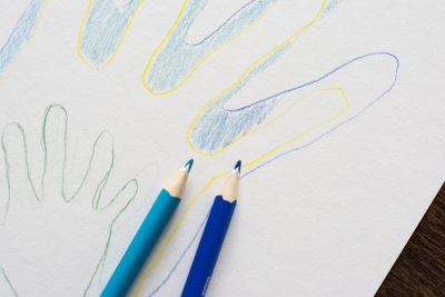 Bunte Handumrisse auf Papier mit zwei blauen Farbstiften