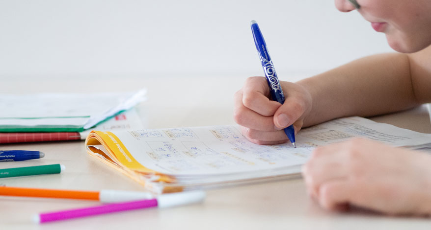 Ein Kind schreibt in ein Lernheft mit einem Frixion Pen von Pilot. 