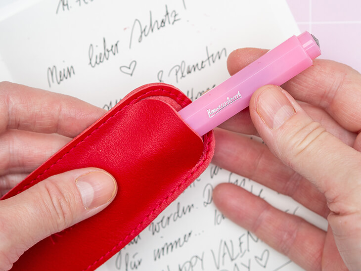 Jemand zieht einen rosa Kugelschreiber von Kaweco aus einem passenden Lederetui in Rot. Foto: Johanna Rundel