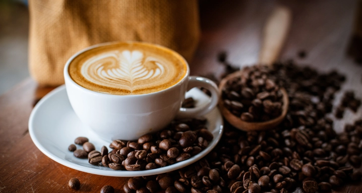 Eine Tasse Kaffee mit Latte Art und Bohnen.