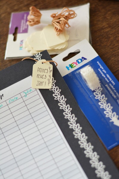 Kalenderblatt mit weißer Bordüre von Heyda und Geschenkanhänger „Frohes neues Jahr“.