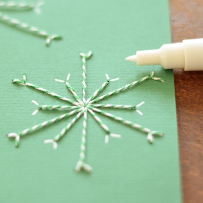 Gestickte Schneeflocke auf grüner Karte mit weißem Marker
