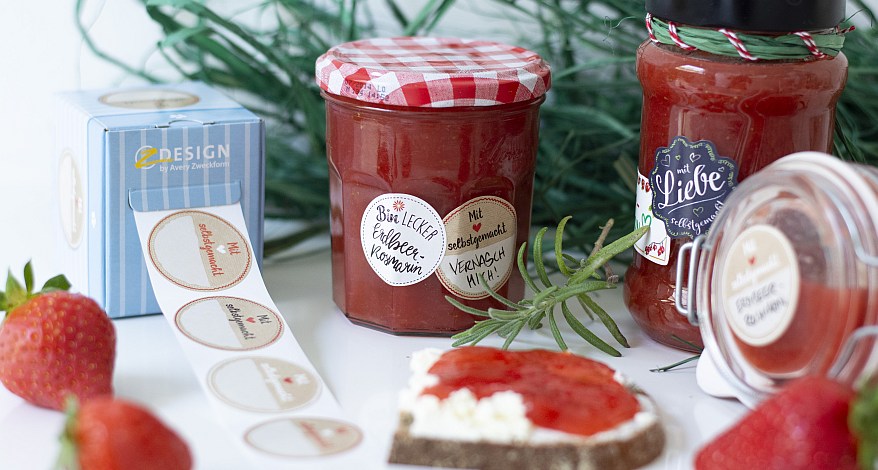 Erdbeermarmeladengläser mit Etiketten, Brot, Erdbeeren und Deko.