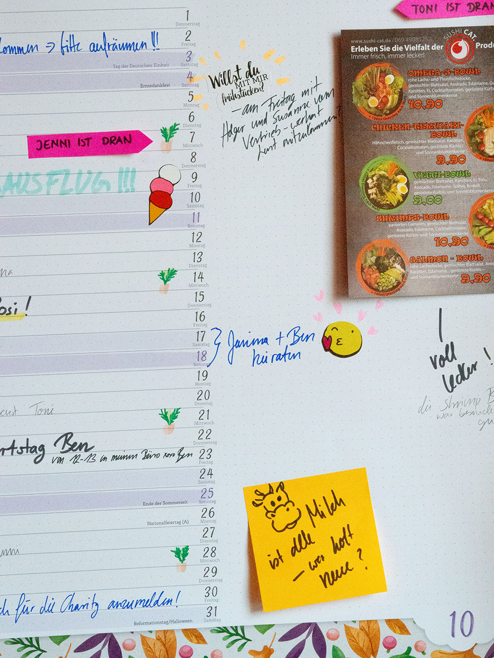 Ein Close-up eines Kalenders der Marke Athesia. Dieser wurde beschriftet und mit Stickern und Haftnotizen beklebt. Auf dem Kalender wurde außerdem ein Flyer eines Restaurants befestigt. 