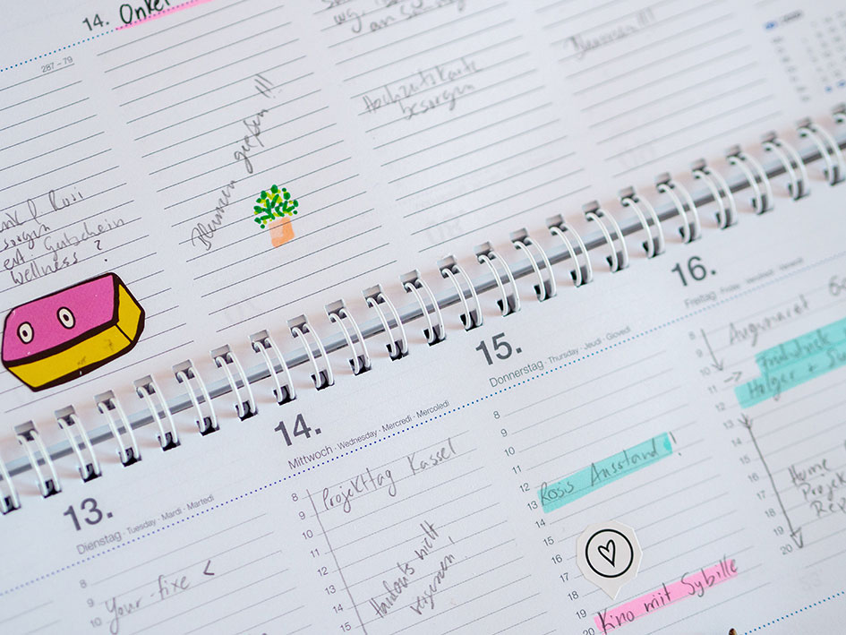 Ein Cloe-up eines aufgeschlagenen Tischkalenders. In diesen sind bereits Termine mit einem schwarzen Stift notiert und teilweise mit Textmarker markiert. 