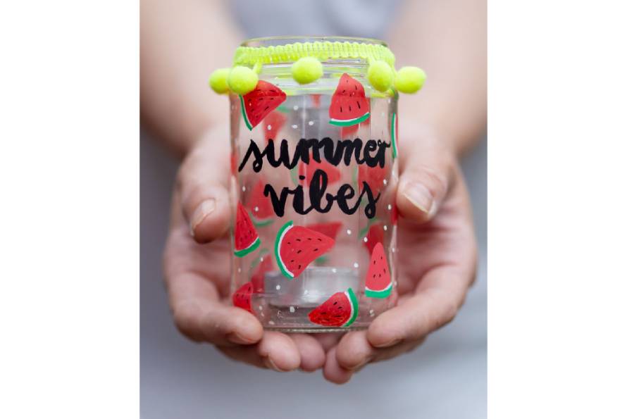 Zwei Hände halten ein selbst bemaltes Glas als Windlicht in die Kamera