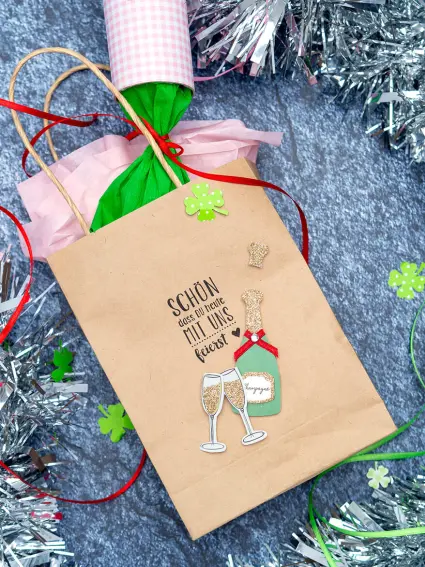 Nahaufnahme einer braunen Papiertüte von KNORR prandell mit Stempelung "Schön, dass du heute mit uns feierst" und Aufklebern von HEYDA. Foto: Johanna Rundel