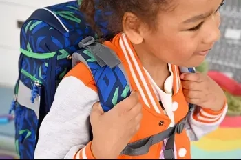 Eine Grundschülerin trägt einen blauen Schulranzen von Step by Step. Dabei hält Sie die Träger mit beiden Händen fest.
