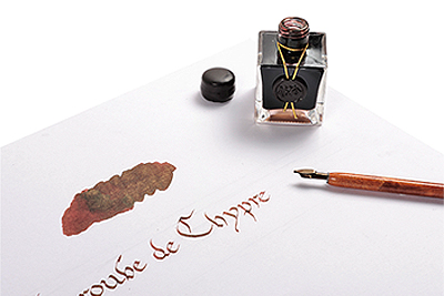 Beschriftetes Blatt, darauf ein Tuschestift und ein Tuschefass