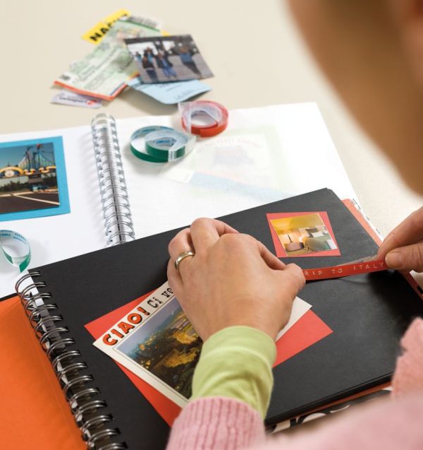 Ein gestaltetes Fotoalbum wird mit beschtrifteten Etiketten beklebt.