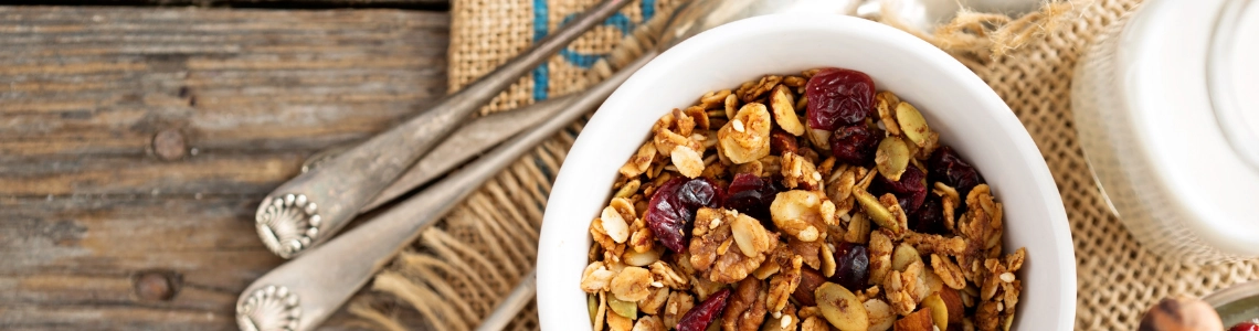 Schüssel mit gesundem Müsli und Milch auf Holztisch