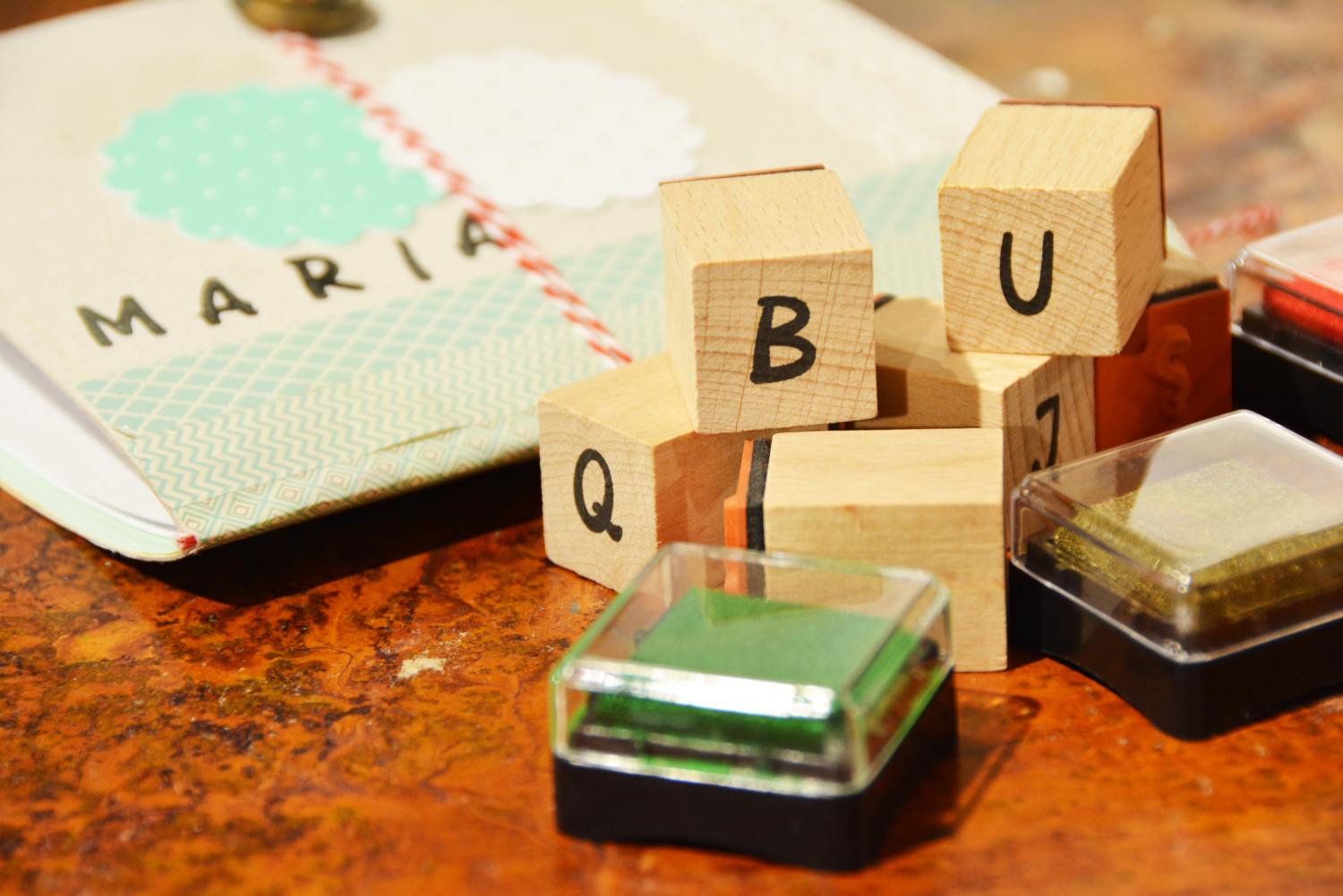 Auf einem Tisch liegen ein selbstgebasteltes Notizbuch sowie Stempel der Marke Heyda mit diversen Buchstaben und ein Stempelkissen.