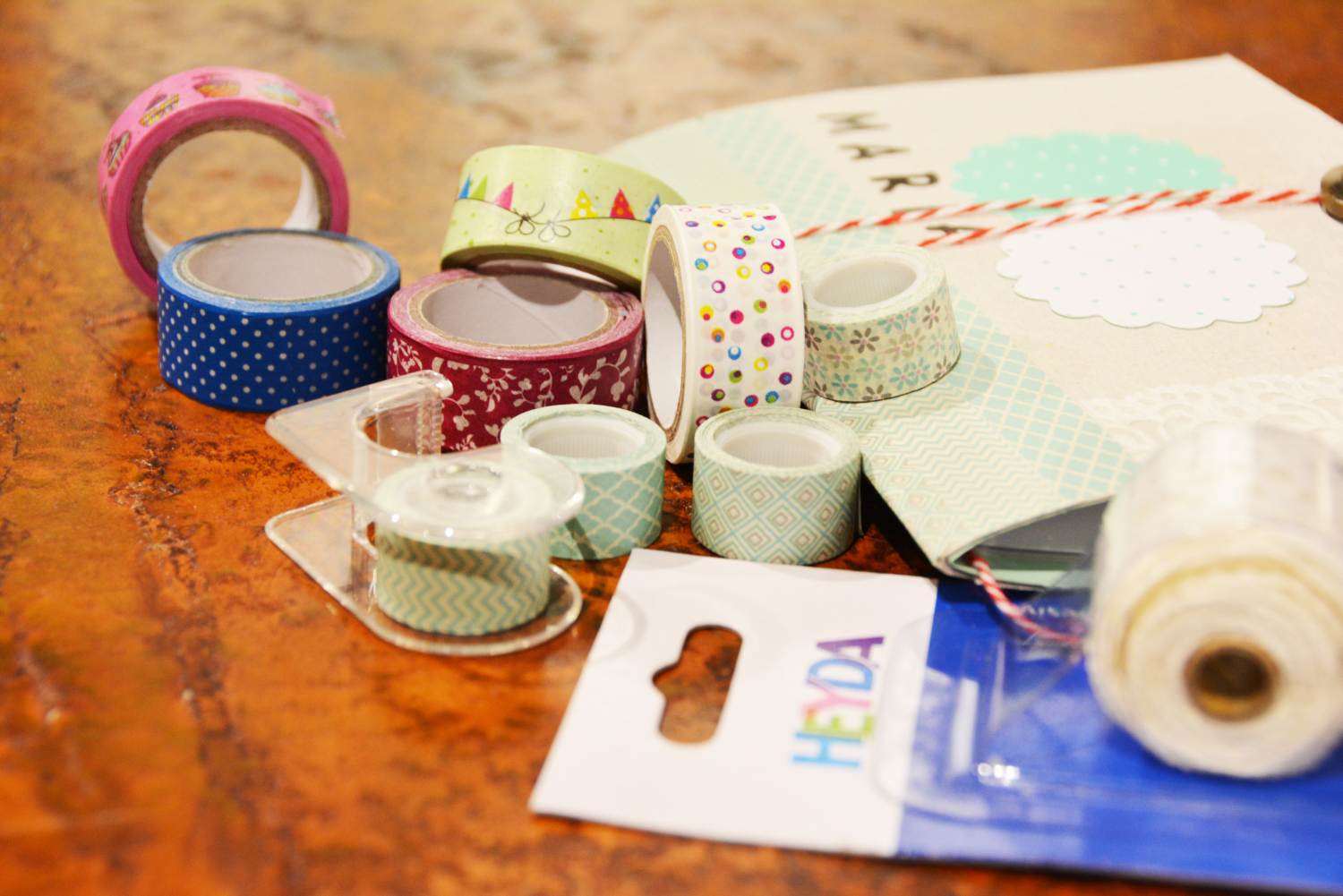 Auf einem Tisch liegen verschiedenfarbige und unterschiedlich große Rollen Washi-Tapr der Marke Heyda.