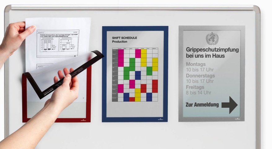 Aushang mit Magnetrahmen wird an Whiteboard neben Dienst- und Impfplan gewechselt.