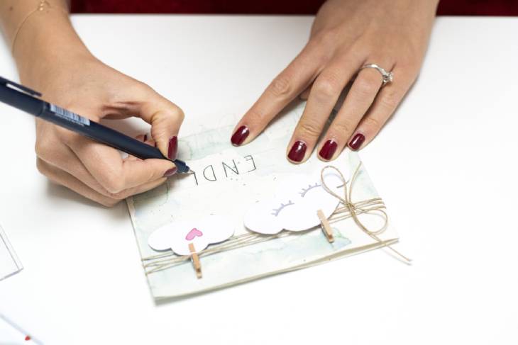 Frau beschriftet DIY-Karte mit schwarzem Stift per Hand