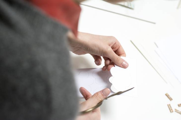 Frau schneidet gezeichnete Wolkenform mit Schere aus