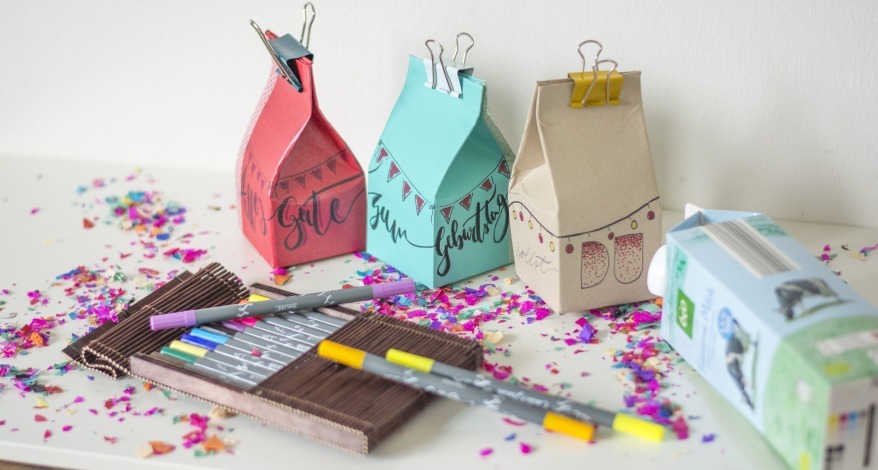 Bunte Geschenkboxen aus Milchkartons mit Stiften und Konfetti